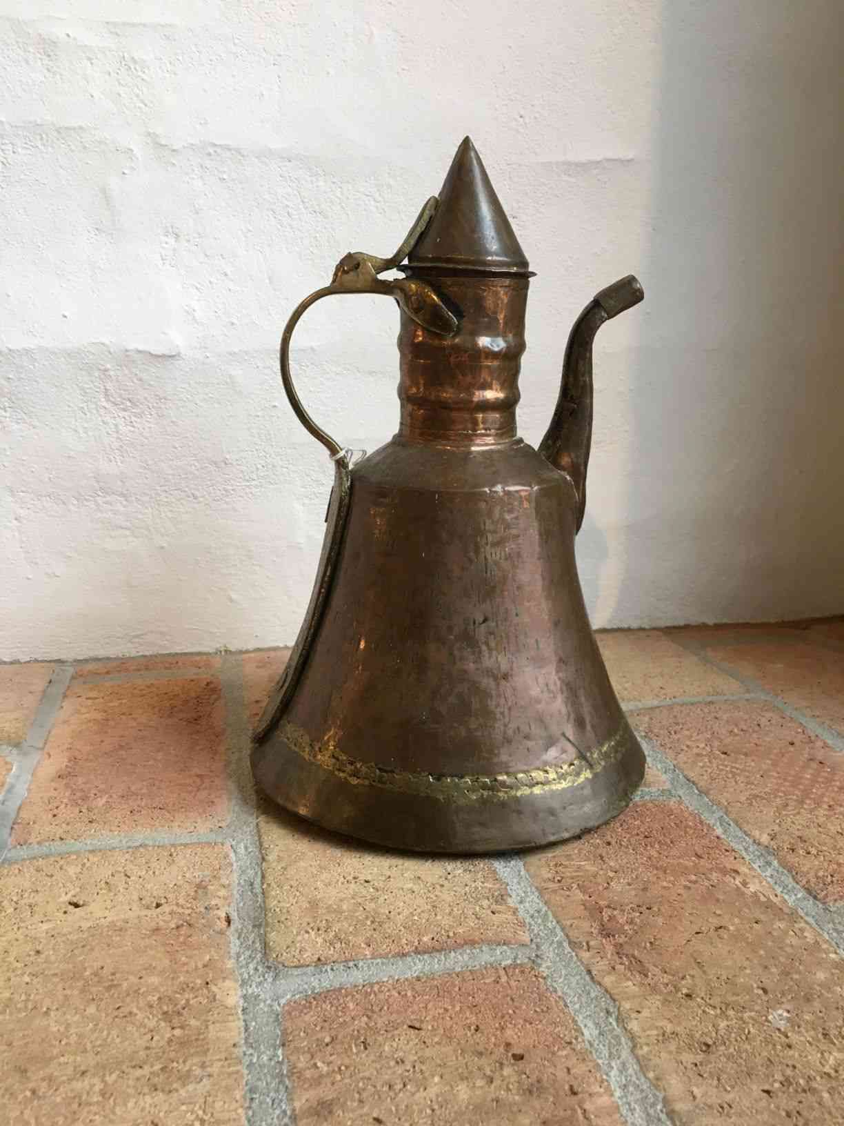 Antik Mellemøstlig, arabisk / tyrkisk hamret kobber Dallah / kaffekande. Den er sandsynlig fremstillet mellem 1850-1899 og er et fantastisk eksempel på gammel persisk islamisk vand- og kaffekande i kobber og messing. Det er en antik og stor kobberbelagt kande, som kan bruges til te, kaffe, vandkogning eller som en dekorativ vase. Den har en flot håndlavet udformning med detaljer, men bemærk, at den er gammel og primitiv med patina og overfladiske mærker, buler og skævheder, der giver den en autentisk følelse. Pris: 350,- Kr.