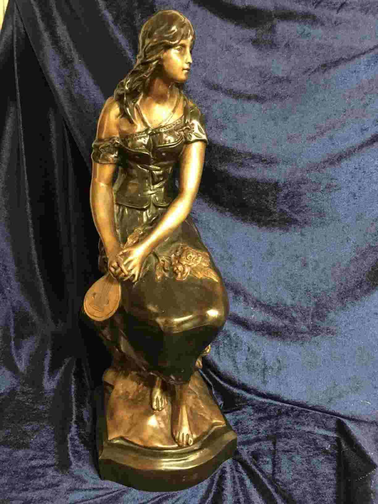 Bronzefigur af ung frodig siddende kvinde med mandolin og et drømmende udtryk. Smukt udført med mange detaljer, en bronze man kan gå på ”opdagelse” i, og hele tiden bygge på historien om denne drømmende musikalske kvinde. 53 cm høj i perfekt stand. Pris: 5.800, - Kr.