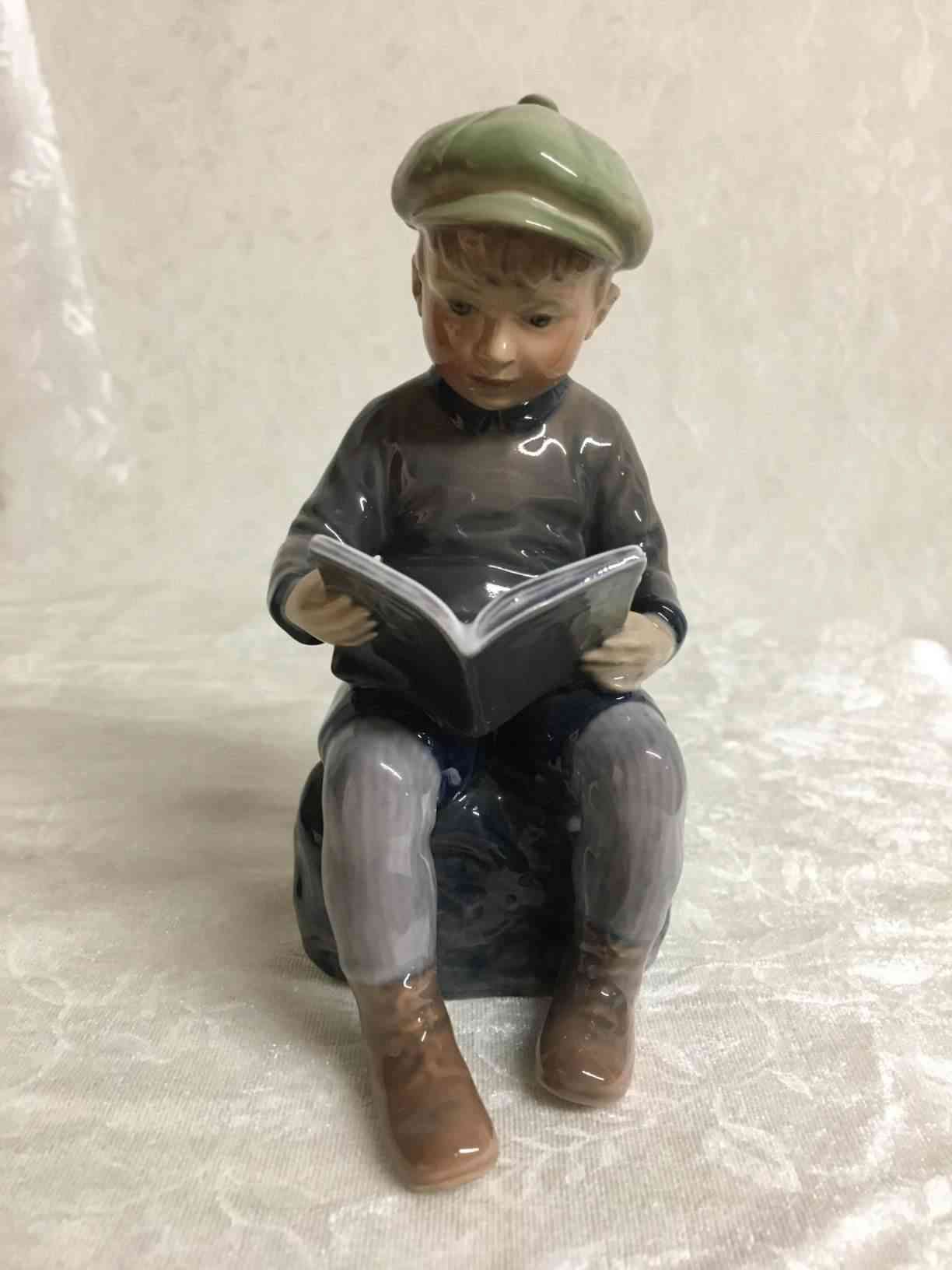 Læsende dreng nr. 1096 med grøn hat, brun trøje og sko samt gråbrun bukser. 1. sortering i perfekt stand. Pris: 1.600,- Kr.