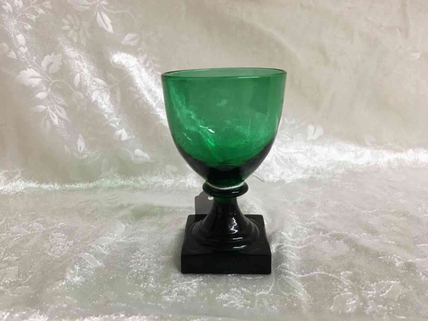 Holmegaard - Gorm den Gamle eller Viking grønt hedvinsglas 9,5 cm i perfekt stand. Pris: 350,- Kr. Glas fremstillet i mørkegrønt glas med kraftig firkantet fod, slebet firkantet eller presset i form, anhæftet mundblæst kumme. Bunden har opstukket "blomst" med runde kronblade. Formen "Skålform" er fra 1900, senere i 1920 udførtes de i mørkegrønt glas blandt andet til glasgrosserer Wiggo Dahl der solgte dem som "Gorm den Gamle". Holmegaard overtog senere forhandlingen af glassene og solgte dem som "Viking". Kastrup har en lignende serie kaldet Emma, dette er dog med slibninger i kummen.